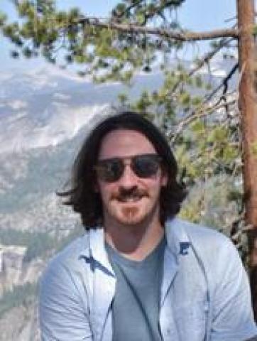 Man with medium-length hair wearing sunglasses in the mountains 