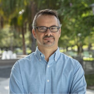 Man in a blue shirt with glasses looking at the camera
